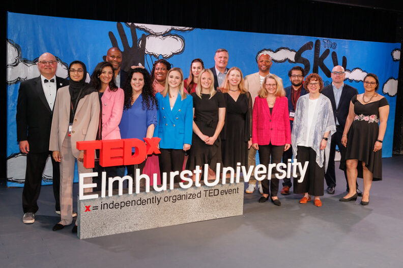 tedxelmhurst大学的一群演讲者在活动标牌前合影留念。