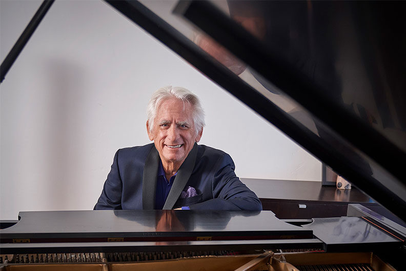 爵士钢琴家大卫·贝努伊特（David Benoit）坐在钢琴上。
